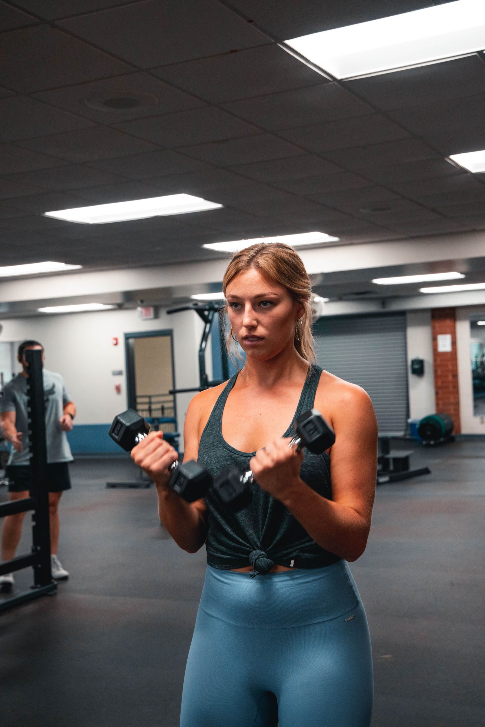 A woman training with dumbbells in a gym
