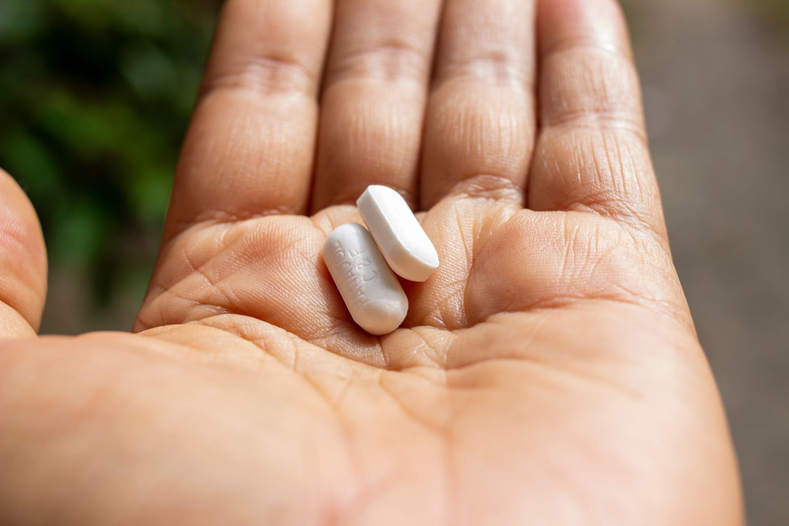 An open palm holding a single white oval tablet