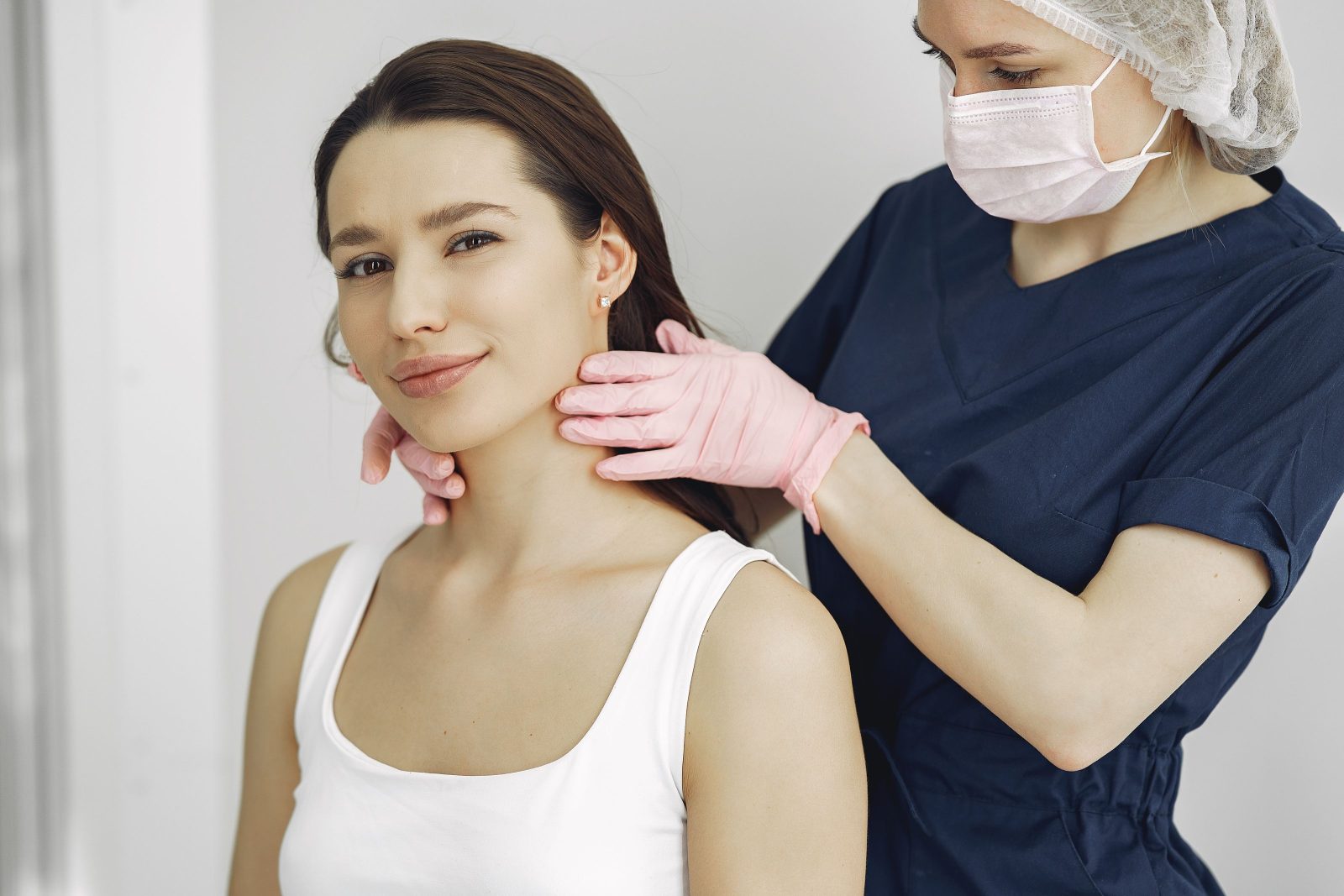 A clinician examining a patient's thyroid gland at the front of the neck